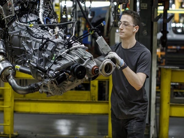 A Ford service tech with safety glasses working on an engine