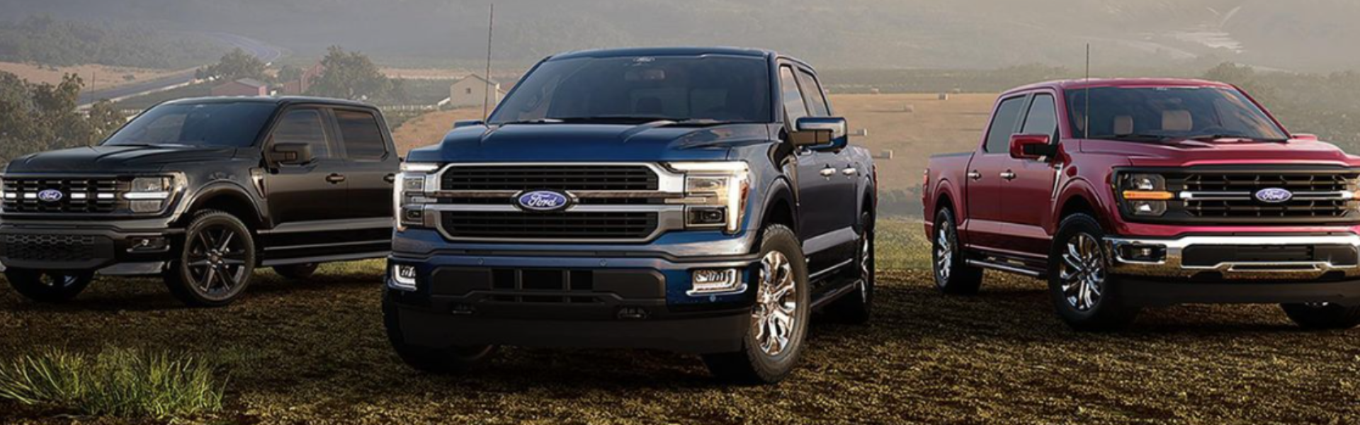 Three 2026 Ford trucks parked with a farm in the background