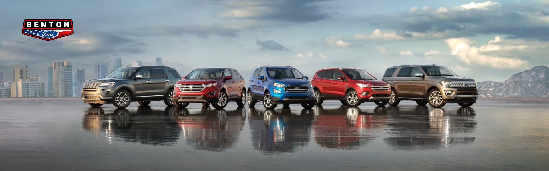 Five new Ford SUVs on a wet ground with mountains to the right and city to the left